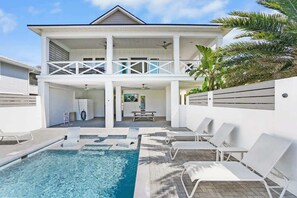 A two-story house with a swimming pool, outdoor seating, and a covered patio area.