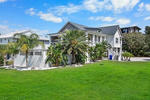 A two-story house with a front porch, a covered patio, and a well-maintained lawn.