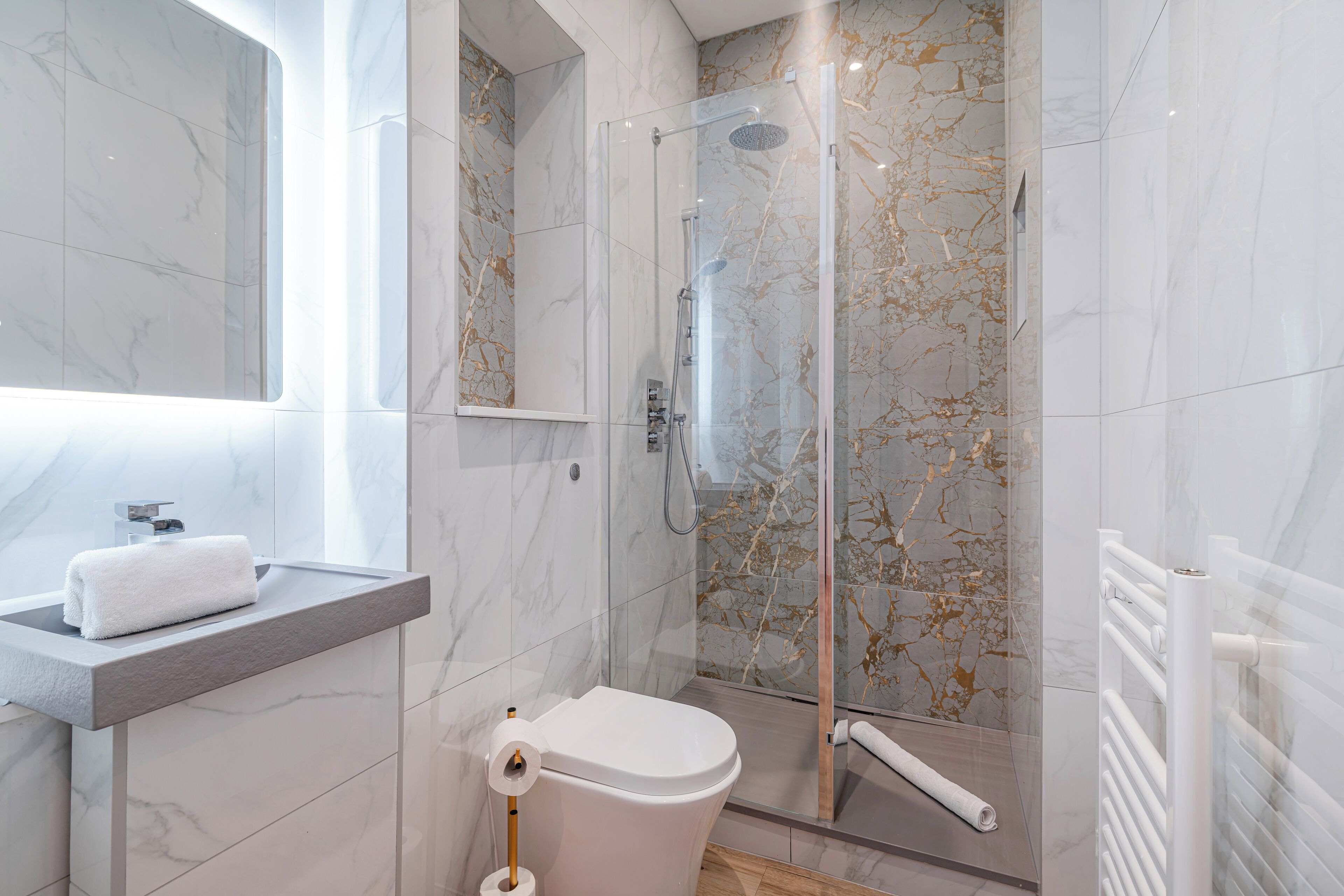 A modern bathroom with a glass-enclosed shower, a toilet, and a sink with a towel.