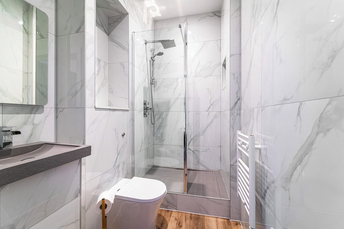 Ein modernes Badezimmer mit Duschkabine aus Glas, Toilette und Waschtisch mit Spiegel.
