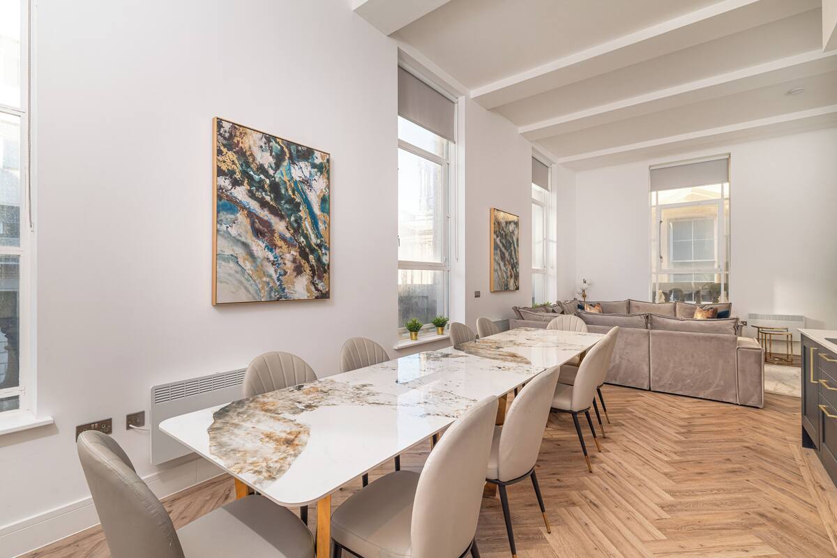 Un comedor moderno con una mesa de mármol, sillas blancas y obras de arte en las paredes.
