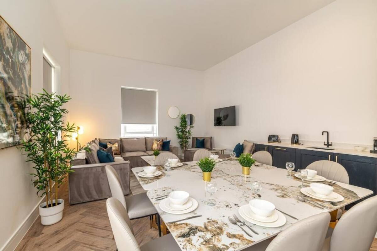 Un moderno comedor con una mesa de mármol dispuesta para cuatro personas, rodeado de asientos cómodos.