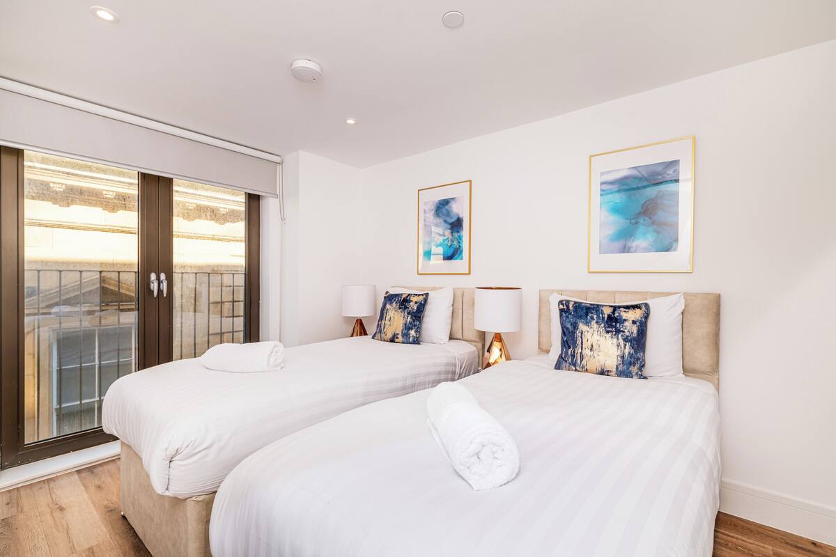 Una habitación de hotel con dos camas, un balcón y obras de arte en las paredes.
