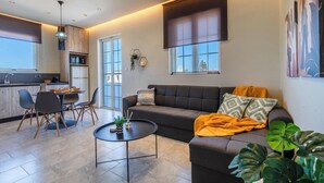 A modern living room with a sofa, coffee table, and dining area.