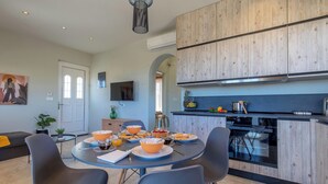 A modern kitchen with wooden cabinets, a built-in oven, and a dining area with a round table and chairs.