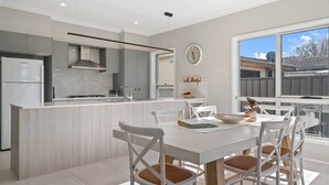 A modern kitchen with a central island, white cabinetry, and a large window providing a view of the outside.
