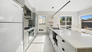 A modern kitchen with white cabinetry, a central island, and a view of the backyard.