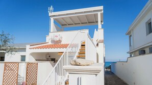A white building with a red-tiled roof, a staircase, and a view of the sea. - Villetta Meraviglia With Garden Sea View (Melendugno)