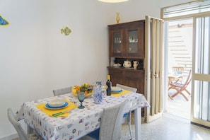 A dining area with a table set for two, a cabinet with glass doors, and a sliding glass door leading to an outdoor area.