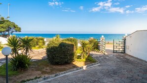 A paved pathway leading to a gate, surrounded by greenery and a view of the sea. - Villetta Meraviglia With Garden Sea View (Melendugno)