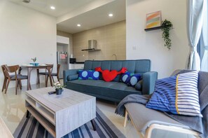 Un salon moderne avec un canapé, une table à manger et des chaises, une table basse et, au fond, un coin cuisine.