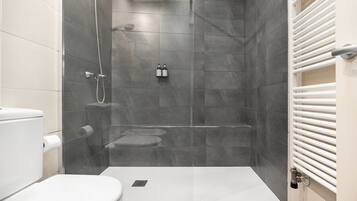 A modern bathroom with a glass-enclosed shower, a toilet, and a bidet.