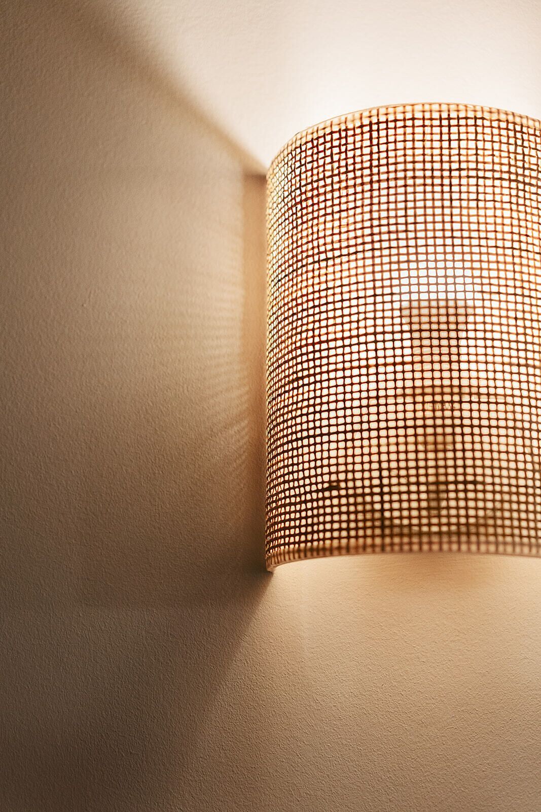 A close-up of a textured wall with a patterned light fixture.