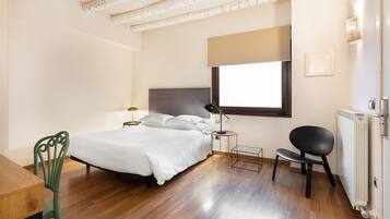 Un dormitorio con cama, mesita de noche, lámpara, silla y radiador.