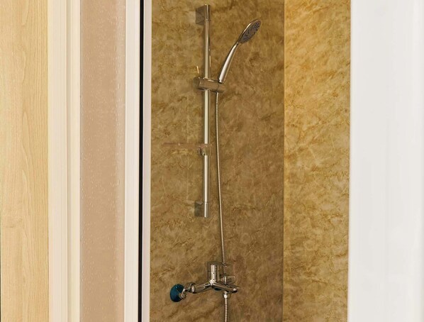 Une douche équipée d’un pommeau de douche à main et d’un robinet fixé au mur.