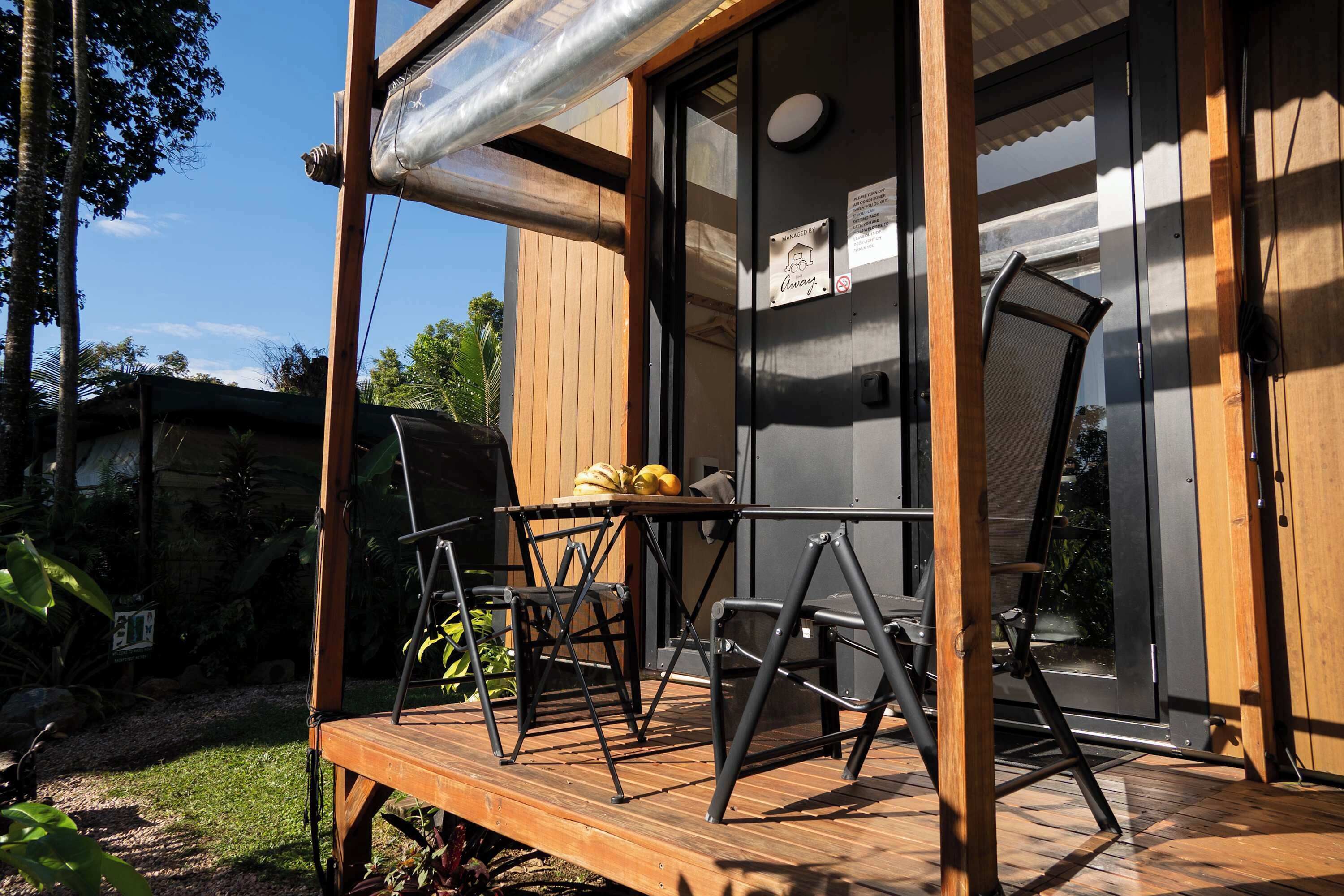 Un patio in legno con mobili da esterno, una porta vetrata e un cartello che indica un ristorante.