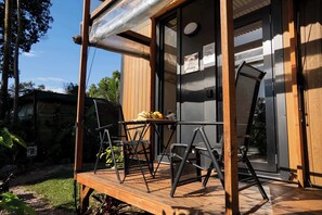 Une terrasse en bois avec des meubles d’extérieur, une porte vitrée et un panneau indiquant la présence d’un restaurant.
