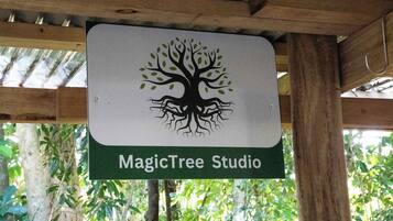 Un letrero con un logotipo de árbol y el texto 'MagicTree Studio' sobre una estructura de madera y un fondo natural.