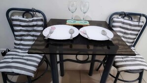 A dining table with two chairs, each with striped cushions.