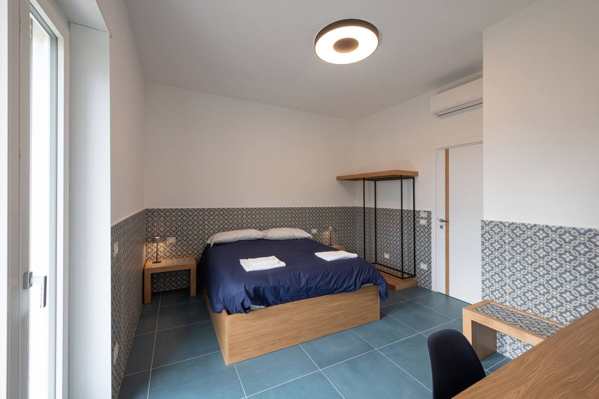 Une chambre à coucher avec un lit, des tables de chevet, un bureau et une chaise.
