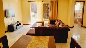 Ein Wohnzimmer mit einer Couch, einem Fernseher, einem Esstisch und einem Deckenventilator.