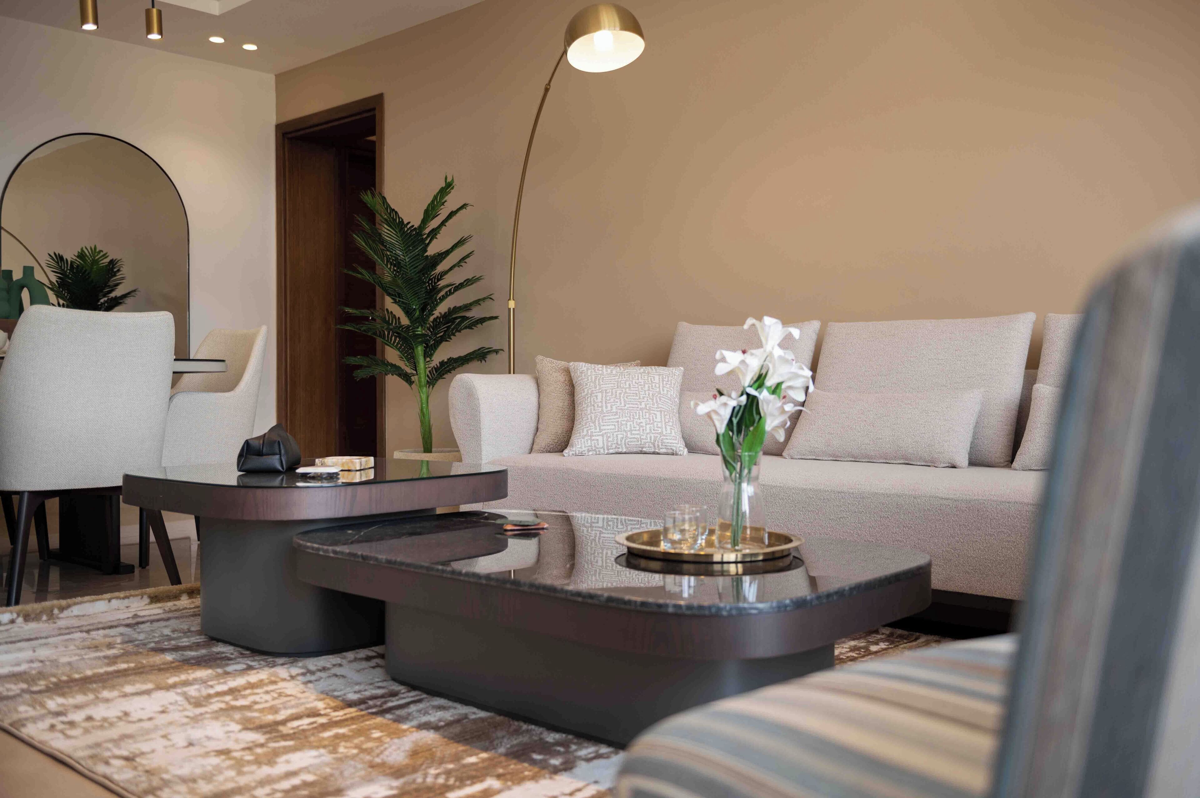A modern living room with a sofa, two coffee tables, and a lamp.