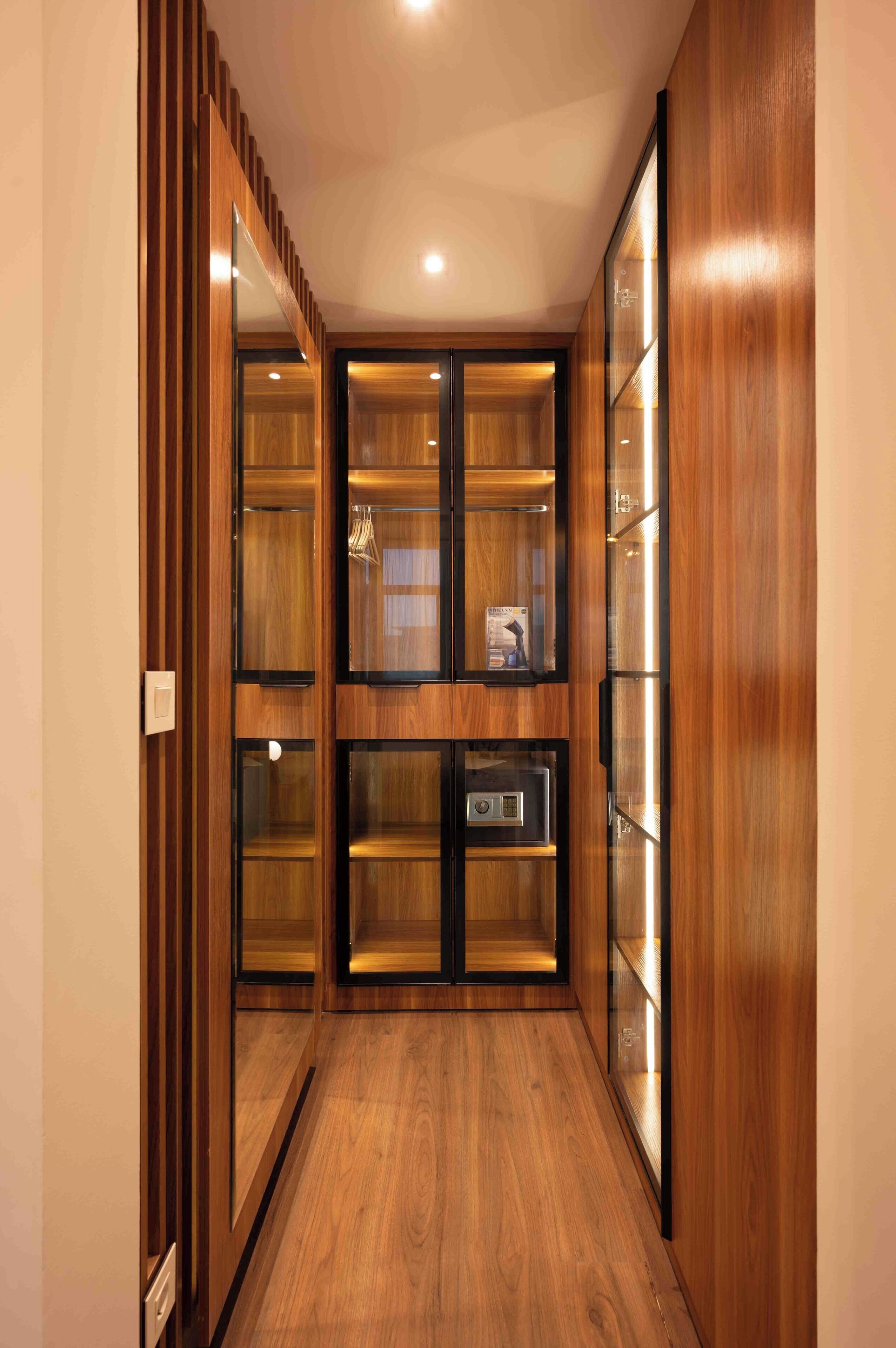 A hallway with wooden paneling and glass-fronted cabinets.