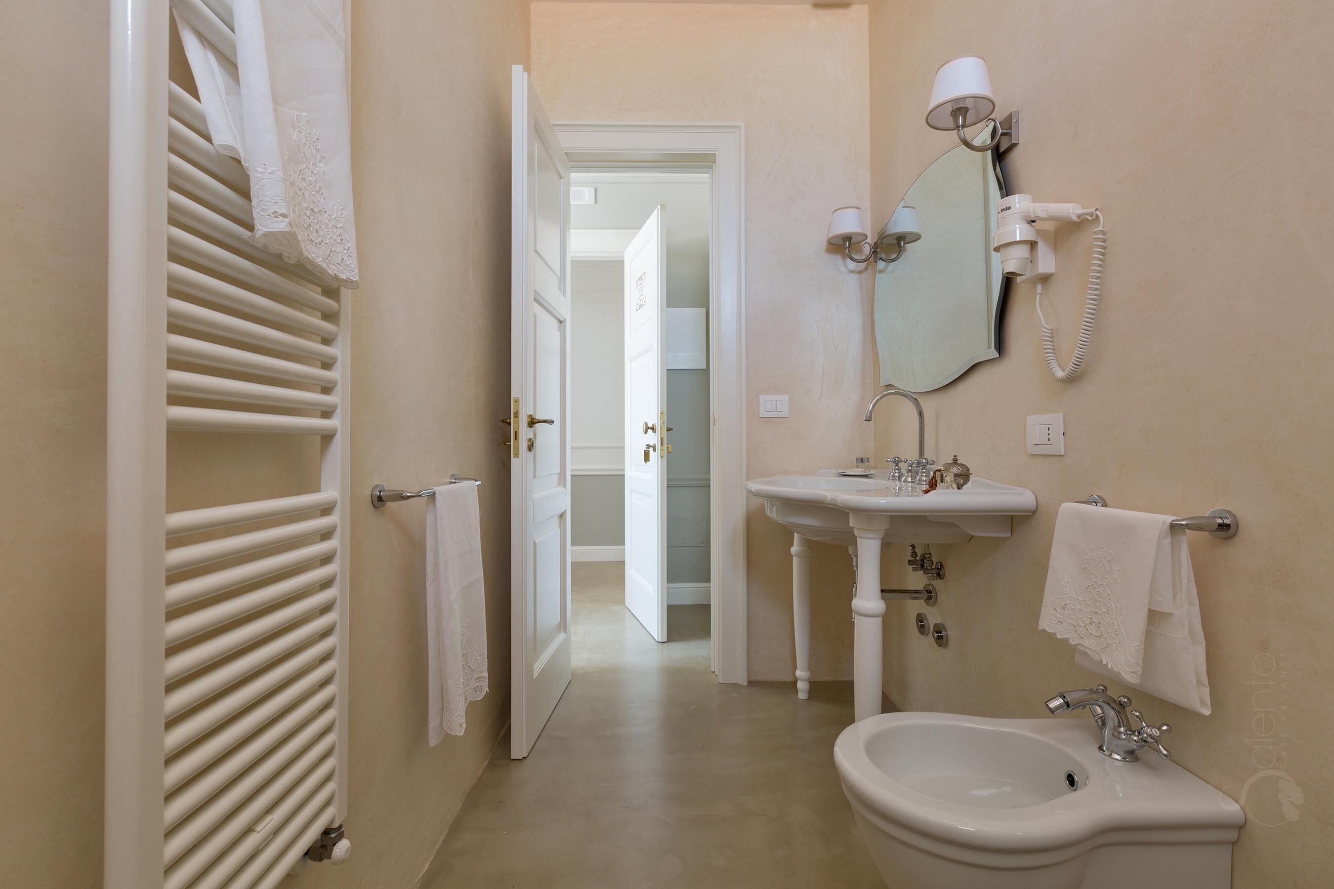 Une salle de bain équipée d’un radiateur, d’un lavabo, d’un bidet et d’un miroir.
