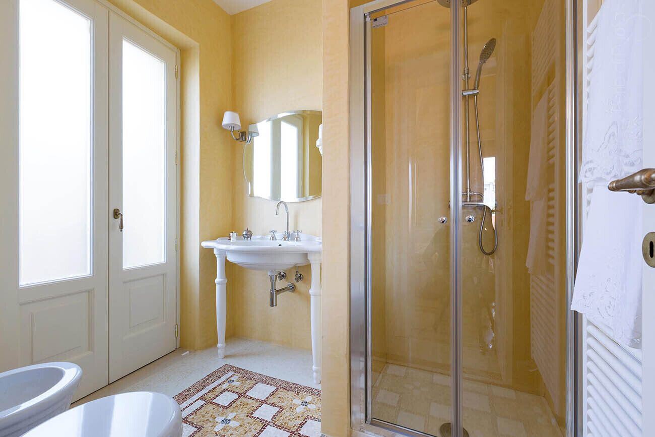 Un baño con ducha de vidrio, lavamanos blanco y un espejo.