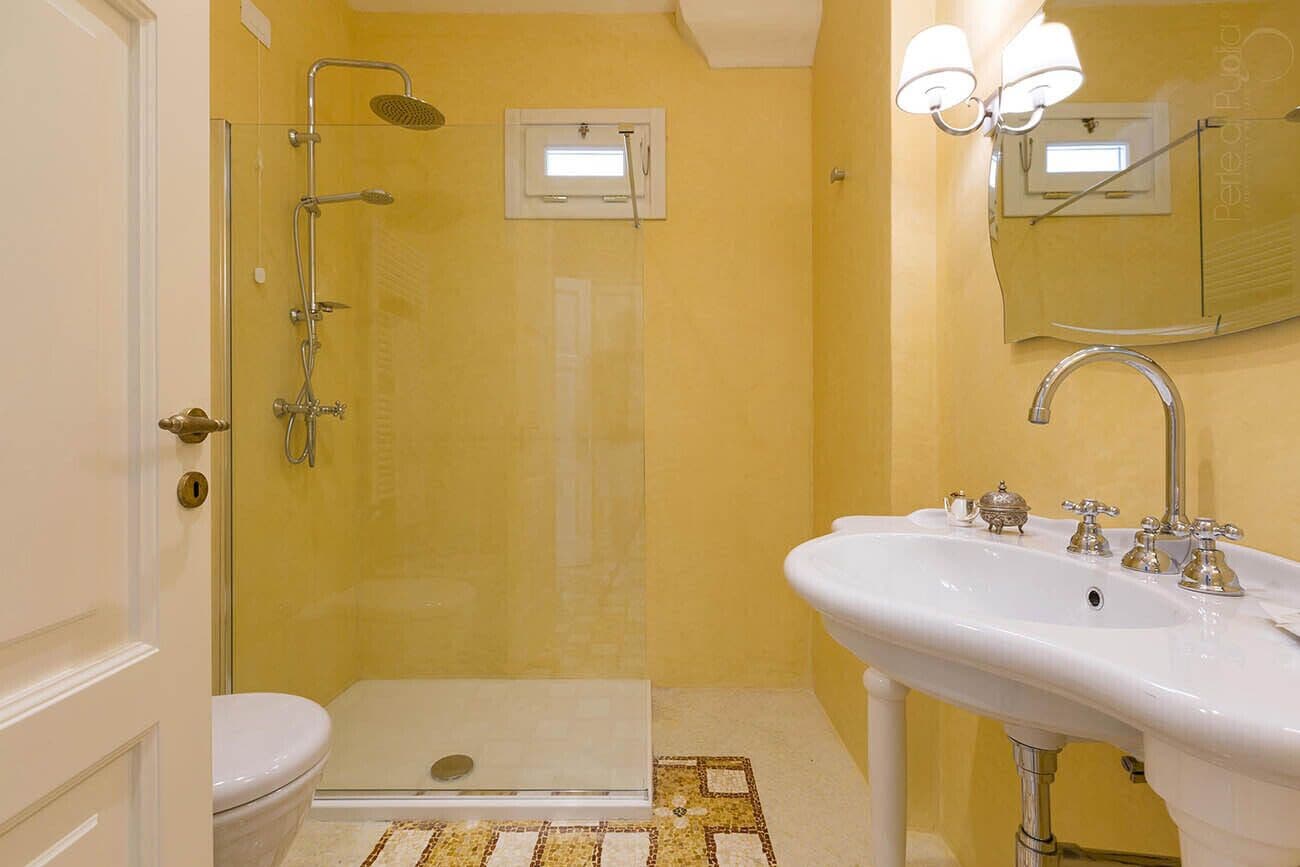 A bathroom with a glass-enclosed shower, a white sink with two faucets, and a mirror above the sink.