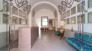 A spacious hallway with a central island, seating area with patterned cushions, and decorative wall art. - Palazzo Fasti (Casarano)