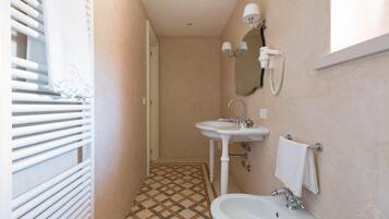 Een kleine badkamer met betegelde vloer, een wastafel, een toilet en een spiegel.