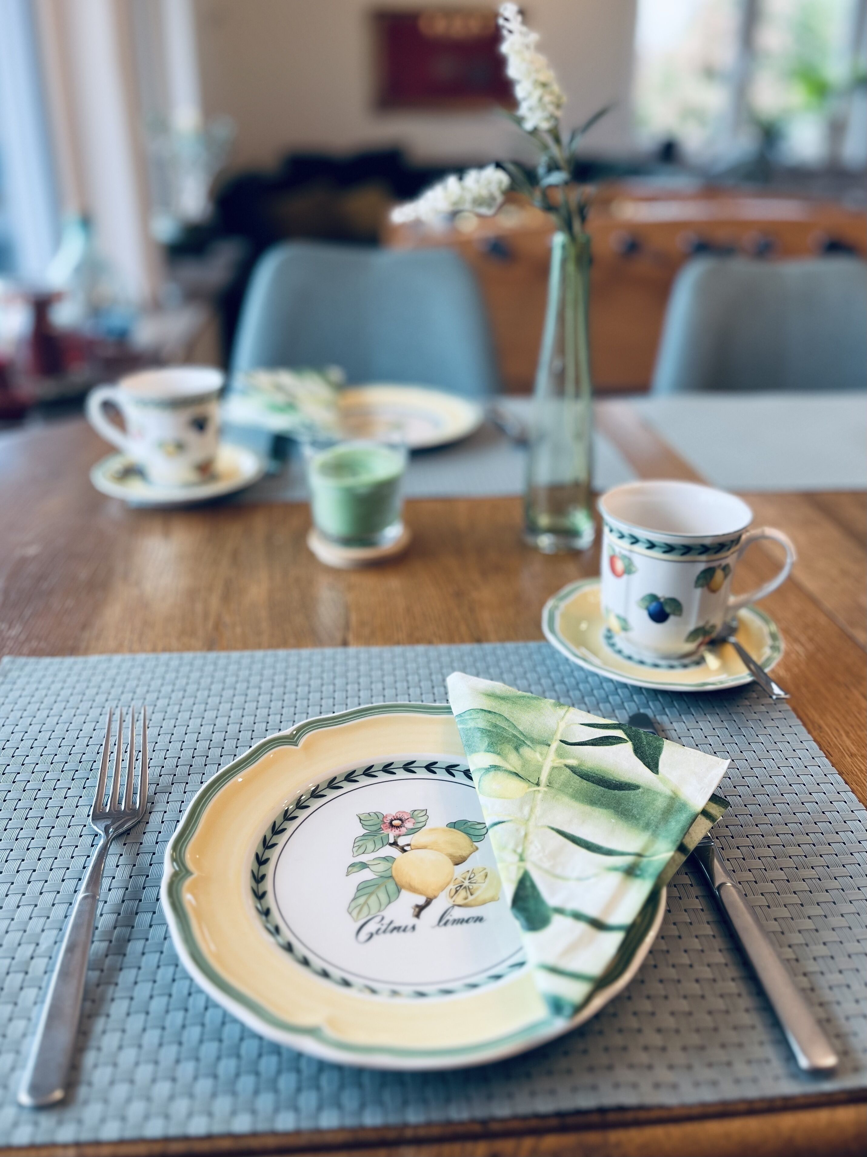 Une table à manger dressée avec des assiettes, des tasses et des couverts.
