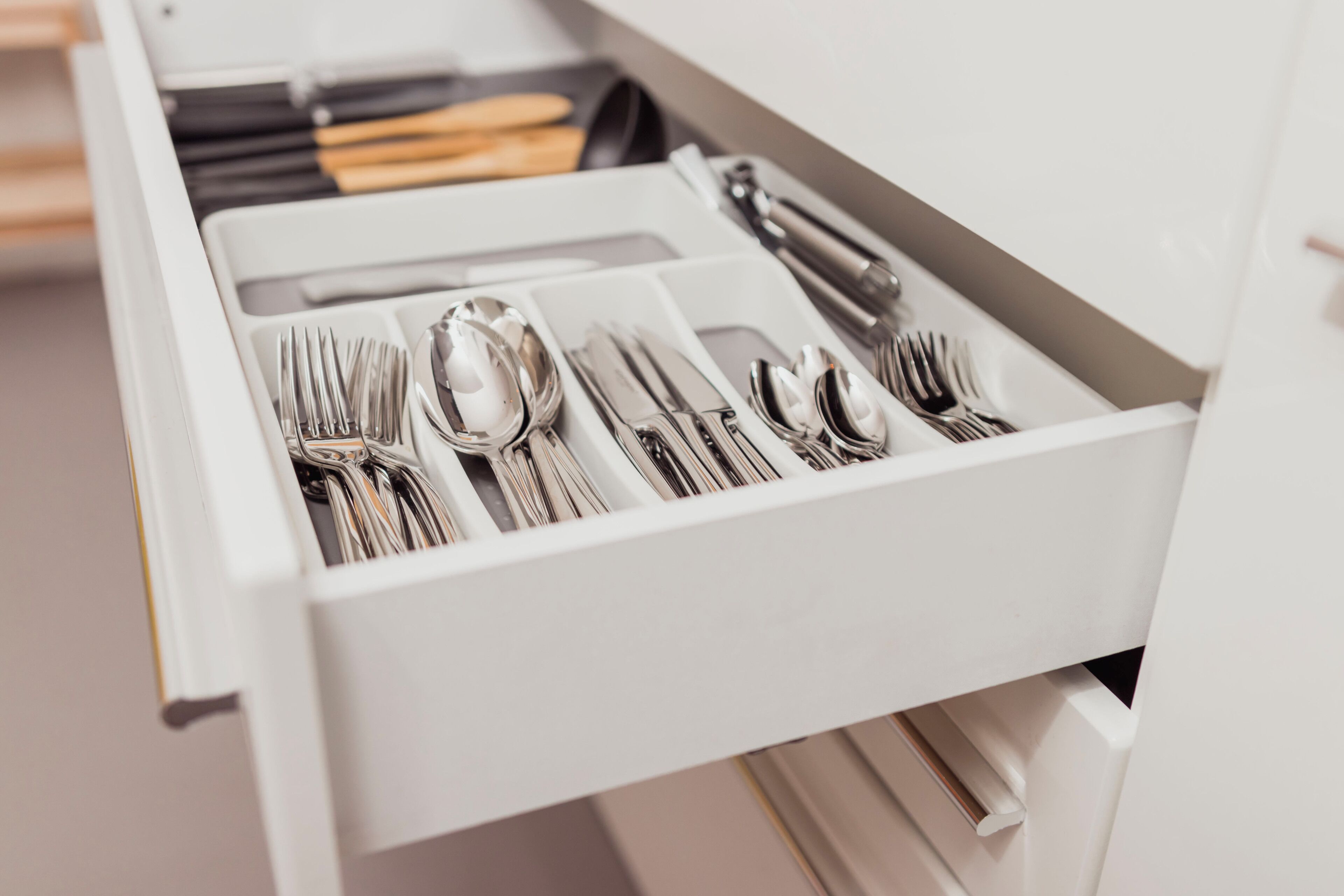 Un cajón con cubiertos ordenados, incluyendo tenedores, cucharas y cuchillos.