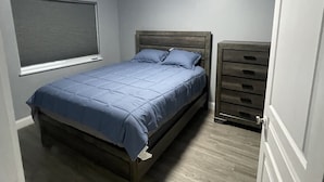 Un dormitorio con cama, cómoda y ventana con persianas.