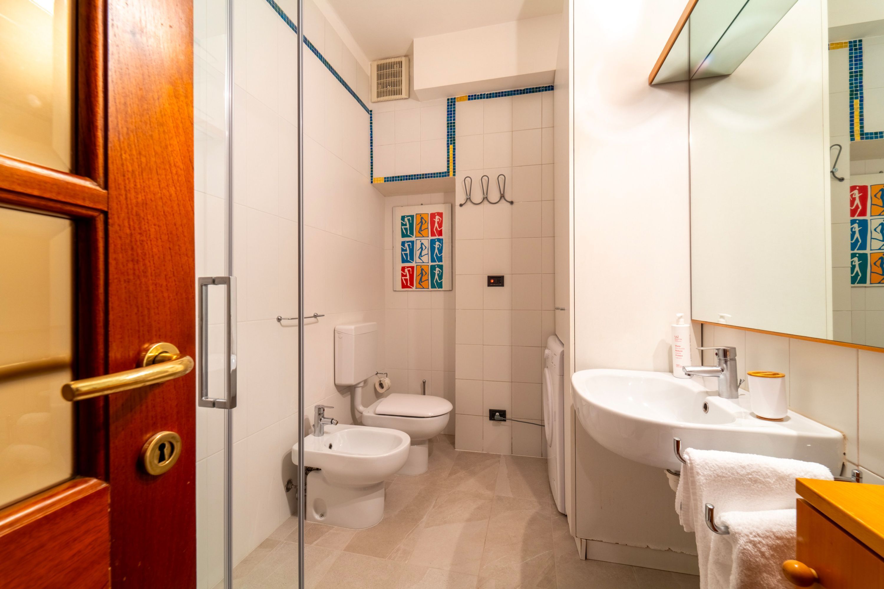 A bathroom with a toilet, bidet, sink, and mirror.