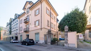 A multi-story building with a beige facade, a gated entrance, and a parking area with cars. - Gerbett Apartment With Terrace by Wonderful Italy (Como)