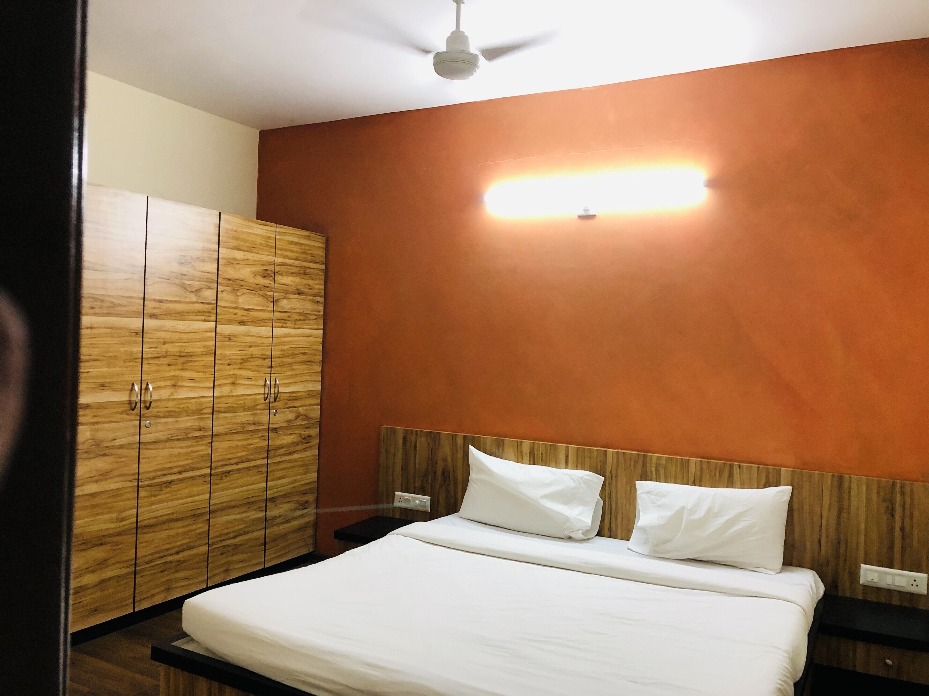 Un dormitorio con cama, armario de madera y ventilador de techo.