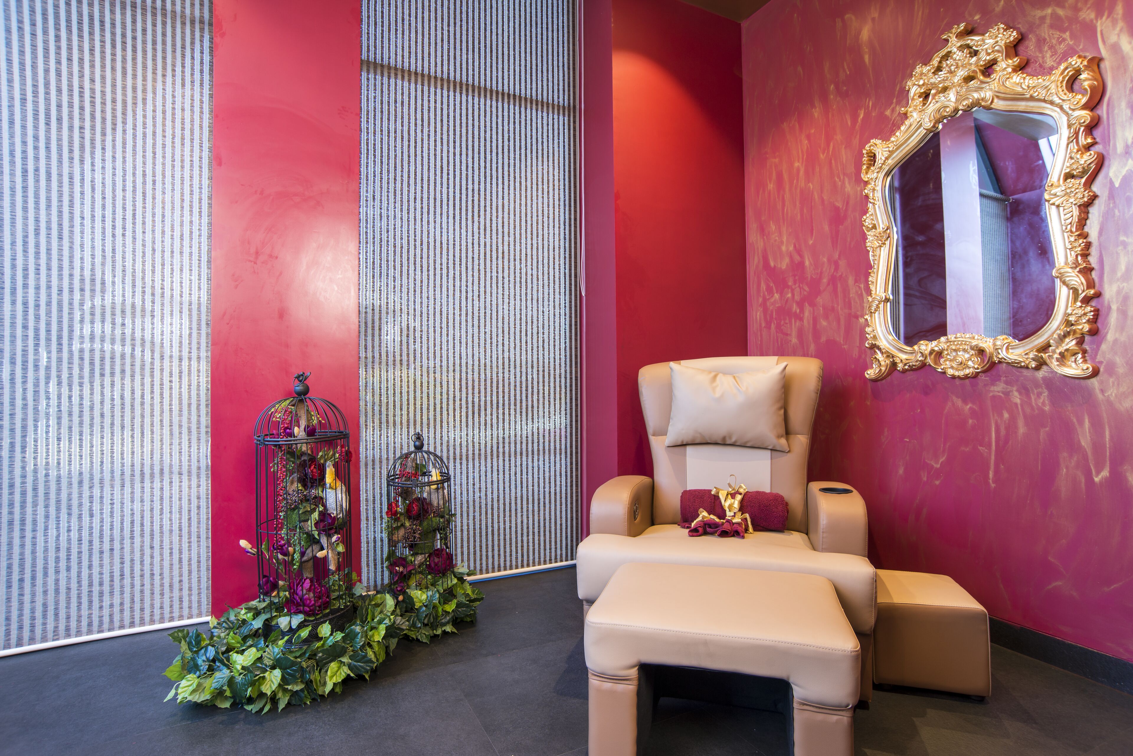 A room with a red wall, a large mirror, a beige sofa, and a small table.