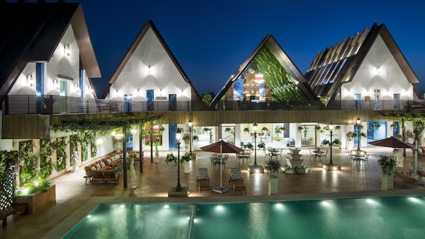 Un hotel con piscina, mobiliario exterior y un patio cubierto.