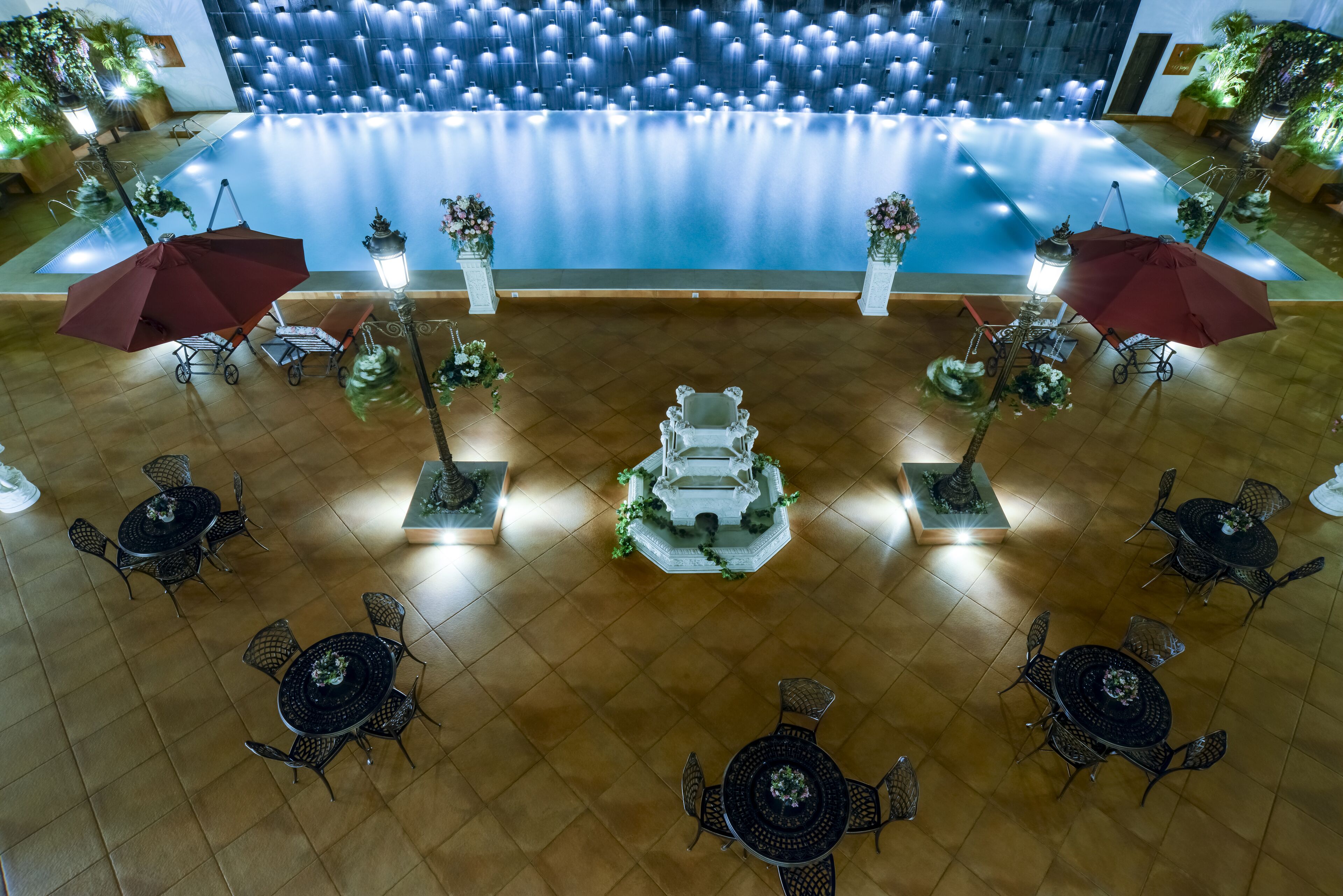 Amplia zona de piscina interior con varios espacios de descanso y detalles decorativos.