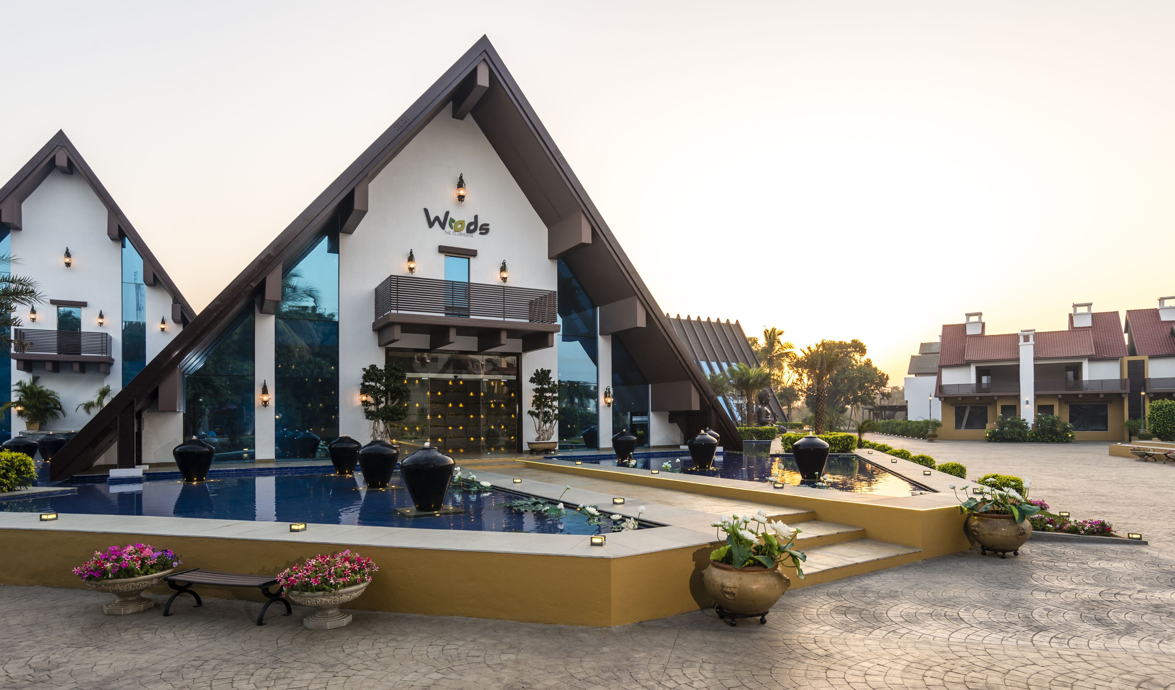 A modern hotel with a distinctive triangular roof, a swimming pool, and outdoor seating areas.