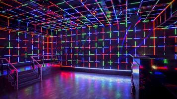 Una habitación con una cuadrícula de luces LED de colores en las paredes y el techo, una escalera y una plataforma.
