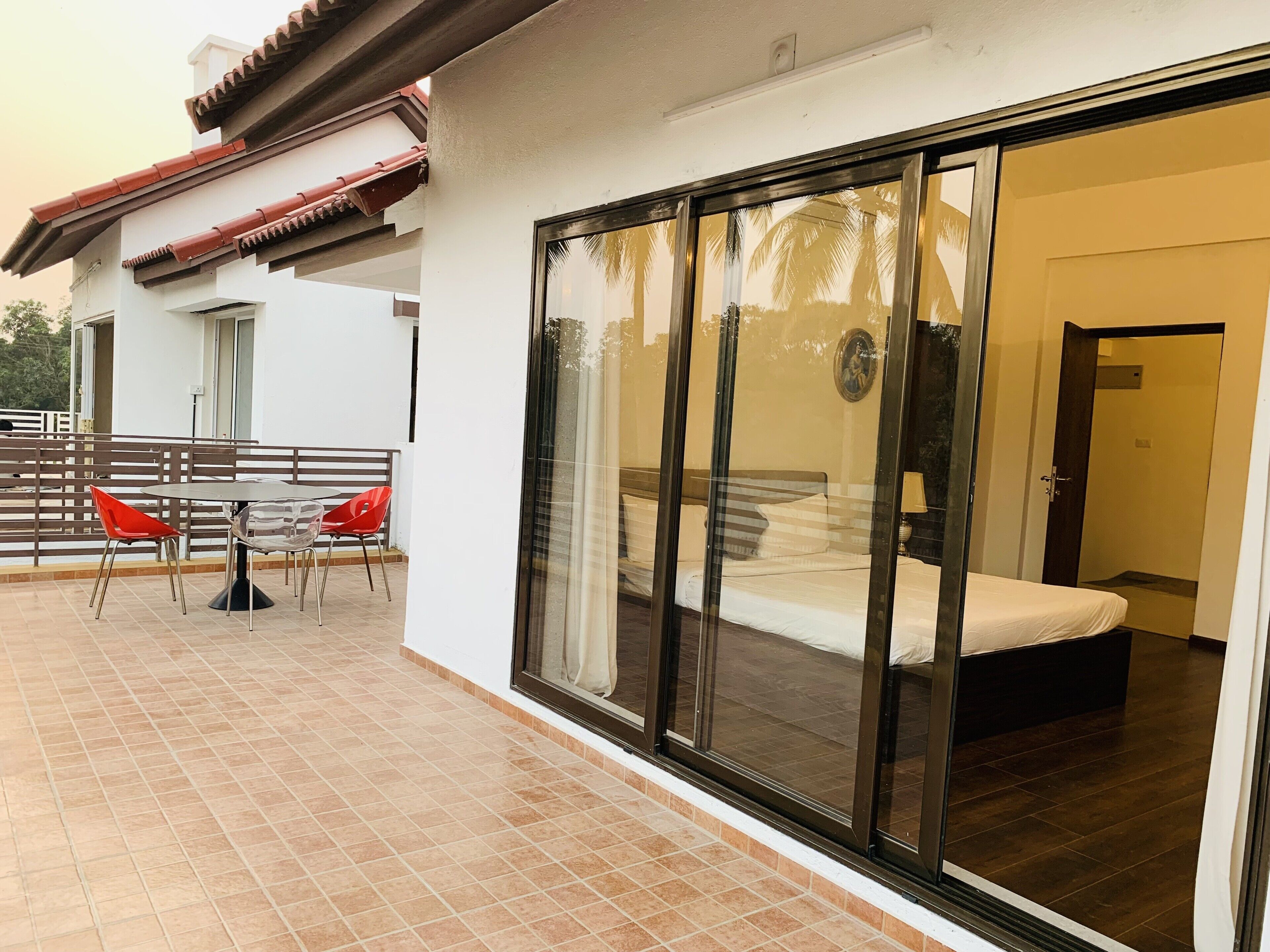 A hotel room with a bed, a bathroom, and a balcony with a table and chairs.