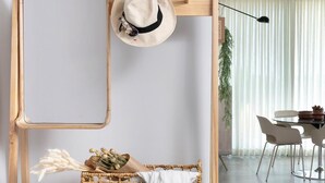 Une étagère en bois sur laquelle sont posés un chapeau, un panier rempli de fleurs séchées et une paire de lunettes de soleil.