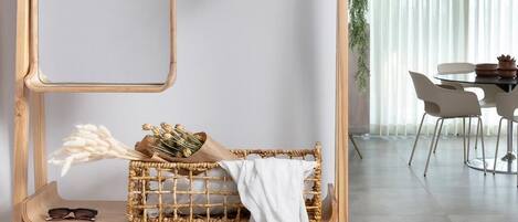 A wooden shelf unit with a hat, a basket with dried flowers, and a pair of sunglasses.