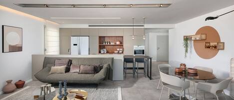 Una sala de estar moderna con sofá, mesa de comedor y zona de cocina.