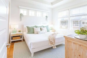 A bedroom with a bed, bedside tables, a nightstand, a window, and a view of buildings outside. - Playa De Bonita by Stay on 30a (Inlet Beach)