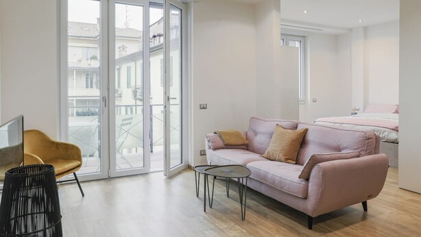 A modern living room with a sofa, a coffee table, and a chair. There is a sliding glass door leading to an outdoor area. - Fuori Le Mura - Balcony & A/C (Como)