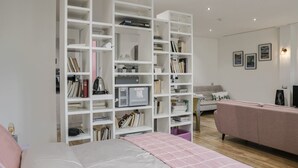 A modern bedroom with a bed, a large white shelving unit, a pink sofa, and a small table with a lamp. - Fuori Le Mura - Balcony & A/C (Como)